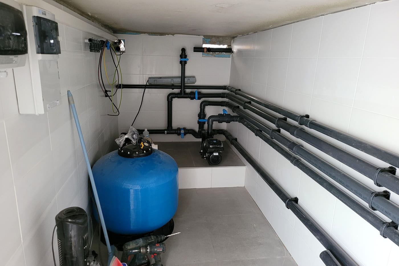 Le même local technique de piscine à Millas terminé : réseau de canalisations monté le long des deux murs