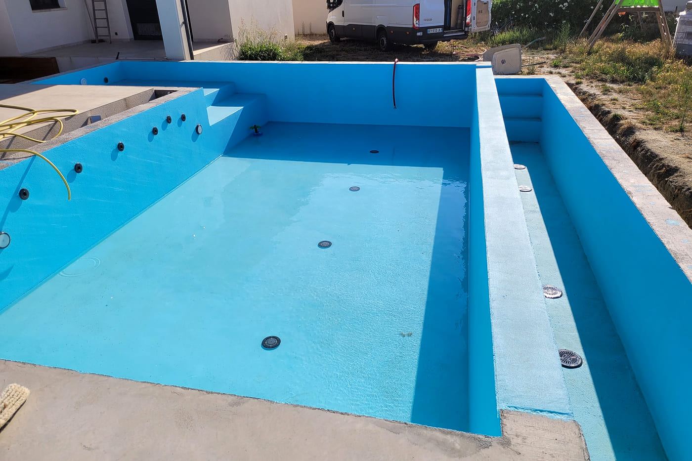 Bassin de piscine en cours de finition à Millas, revêtement bleu posé